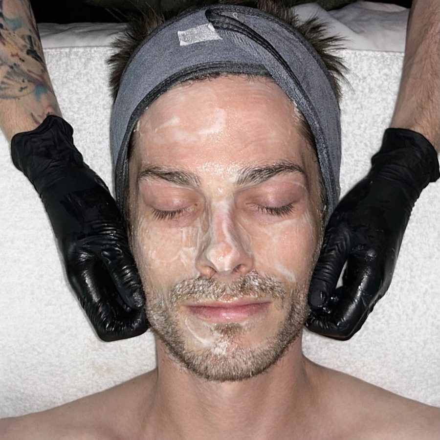 Men's facial treatment cleanser application with black gloves overhead view at Awaken Zen Spa in Mesa, AZ